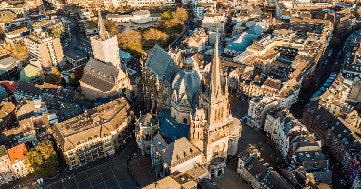 Aerial view of a Gothic cathedral with twin spires surrounded by historic city buildings and streets