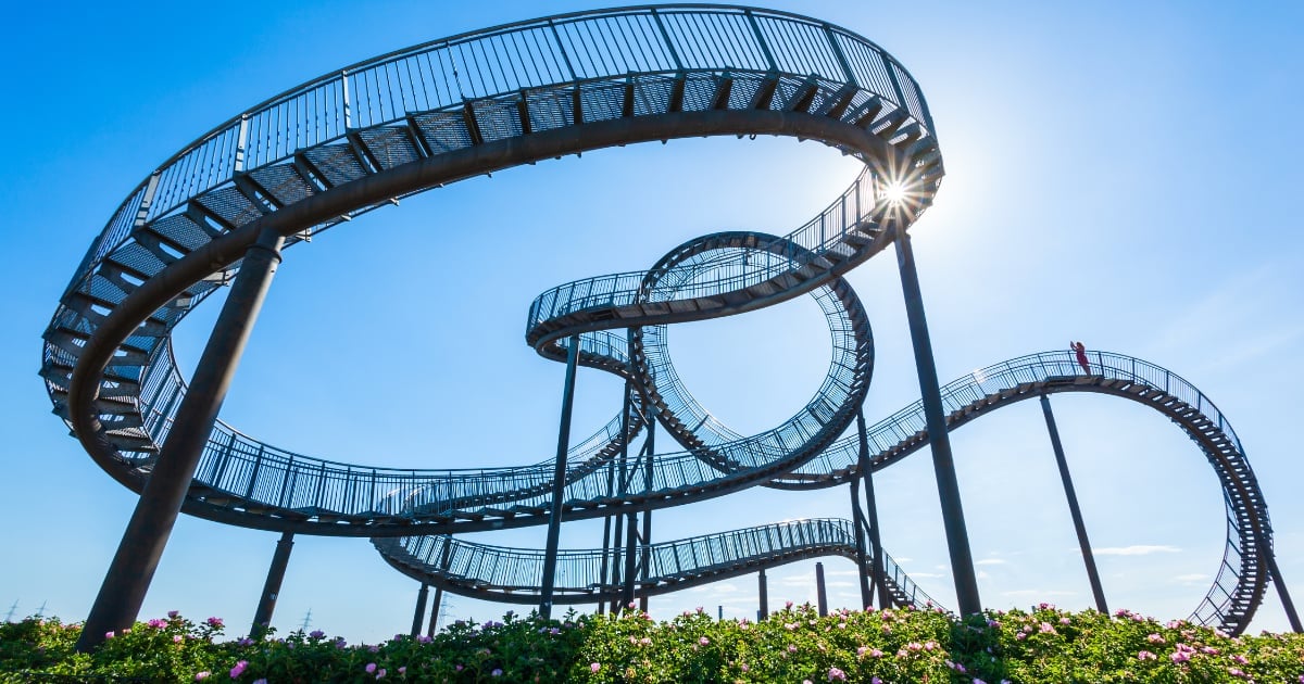 Roller coaster tracks with loops and twists against a clear blue sky