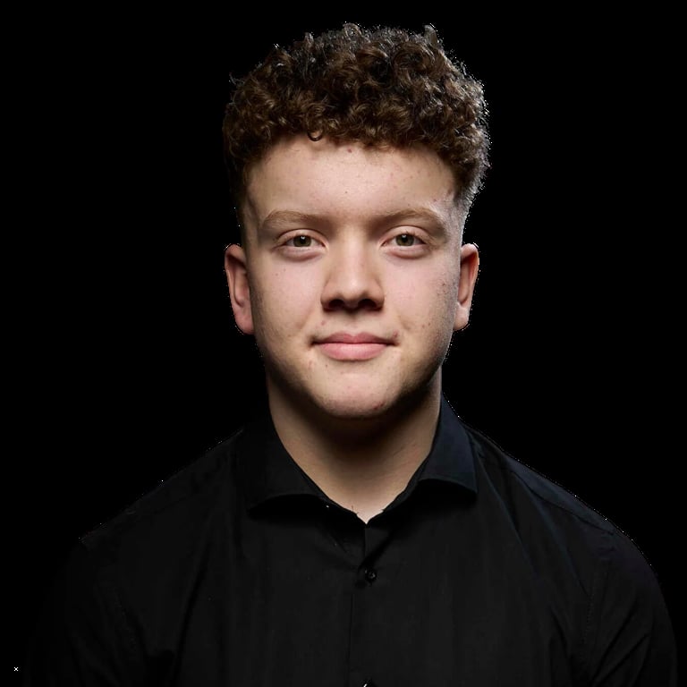 Portrait of a young man with curly brown hair wearing a black shirt against a dark background