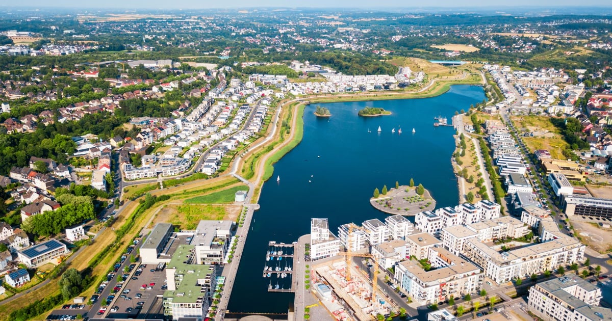 Aerial view of a blue-water lake surrounded by residential neighborhoods and apartment buildings in an urban area
